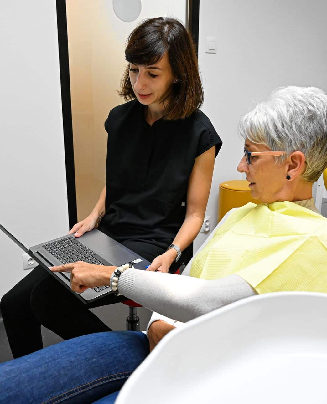 Fogpótlás előtt fogorvos kezében egy laptoppal és páciens aki rámutat