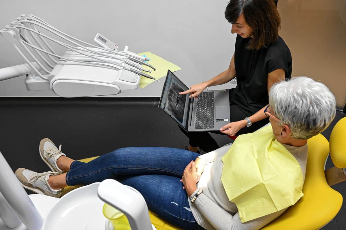 Fogpótlás előtt fogorvos kezében egy laptoppal röntgen felvételt mutat a páciensnek