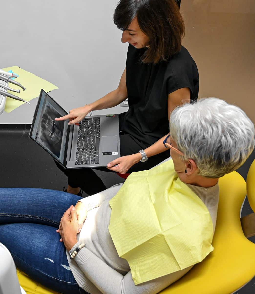 Fogpótlás előtt fogorvos kezében egy laptoppal röntgen felvételt mutat a páciensnek