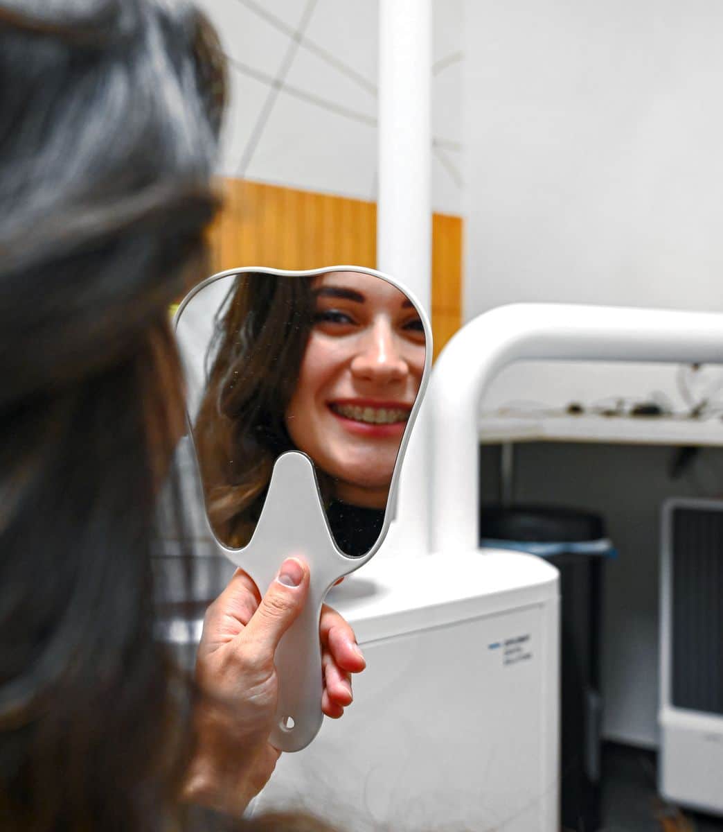 Fogpótlás után páciens tükörben nézi az eredmény a Denteo fogorovosi rendelőben