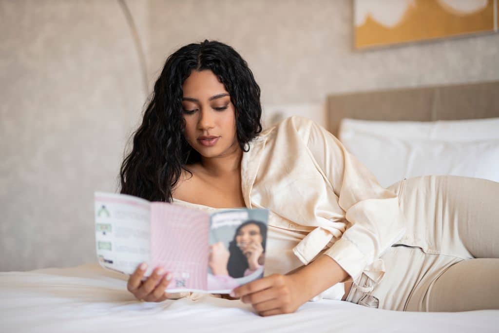 Brossúrát néz a láthatatlan fogszabályozásról egy nő köntösben